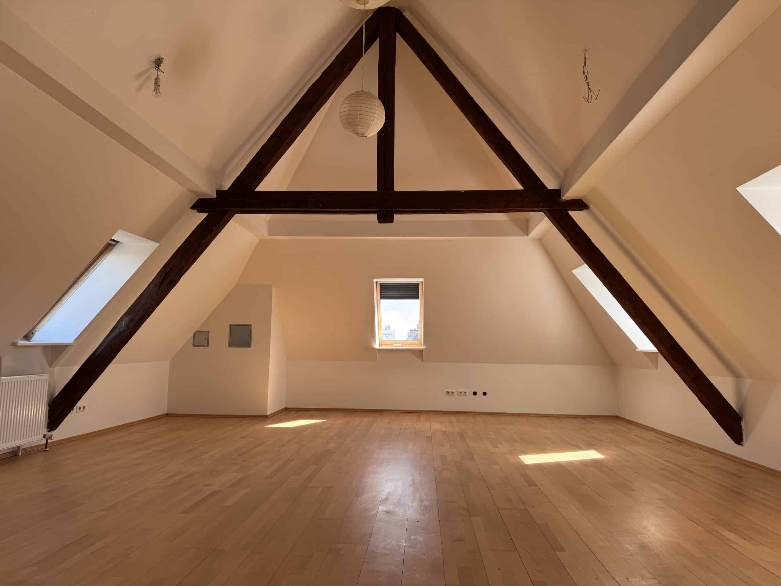 Ein großes Dachgeschoss mit Holzfußboden und Holzbalken