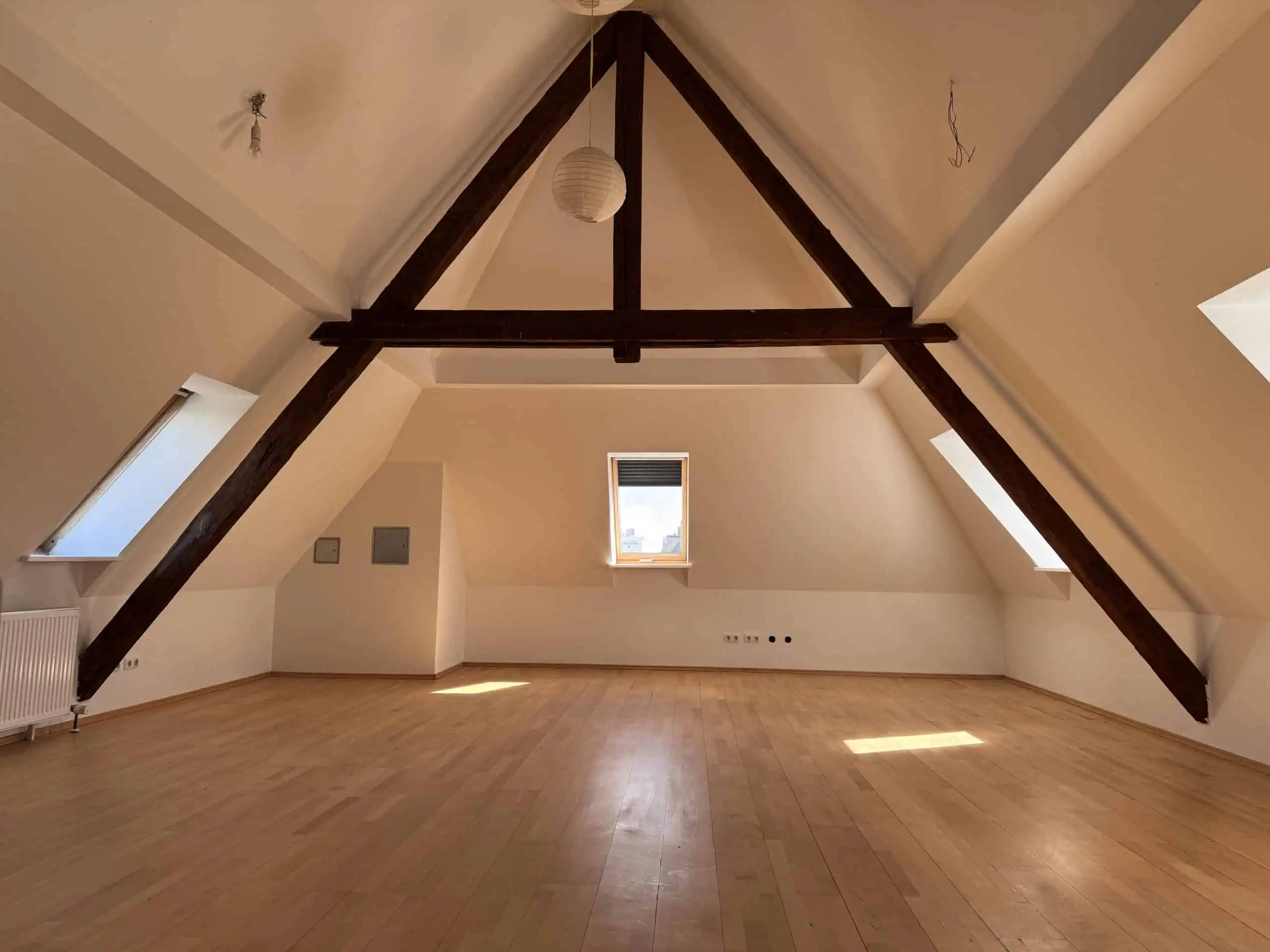 Ein großes Dachgeschoss mit Holzfußboden und Holzbalken